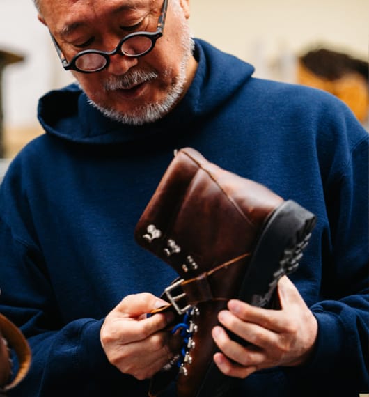 Daiki Suzuki inspecting a hiking shoe with the sole facing outward. A quote from the creative director of Engineered Garments is included.  