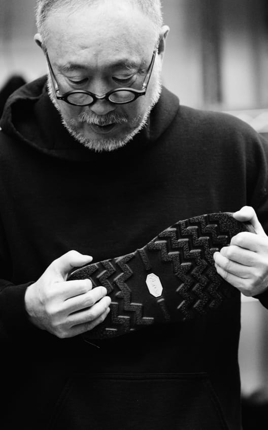 A man holding a lug sole shoe with the sole facing away from him.  